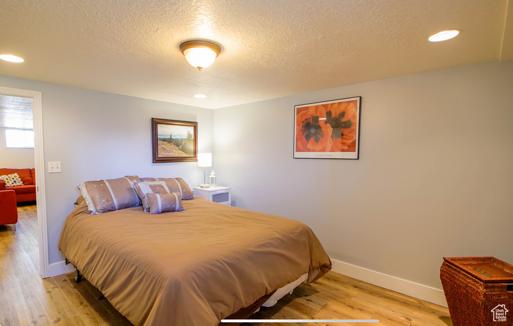 Bedroom with light wood-style flooring, a textured ceiling, baseboards, and recessed lighting