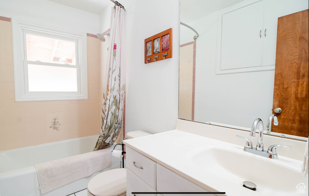 Bathroom with toilet, vanity, and shower / bath combo with shower curtain