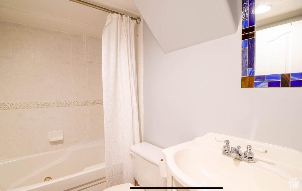 Bathroom featuring toilet, a sink, and shower / bath combination with curtain