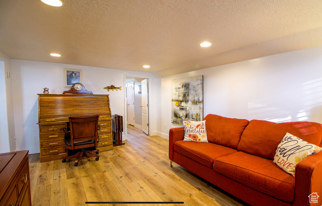 Home office with a textured ceiling, light wood-type flooring, recessed lighting, and baseboards