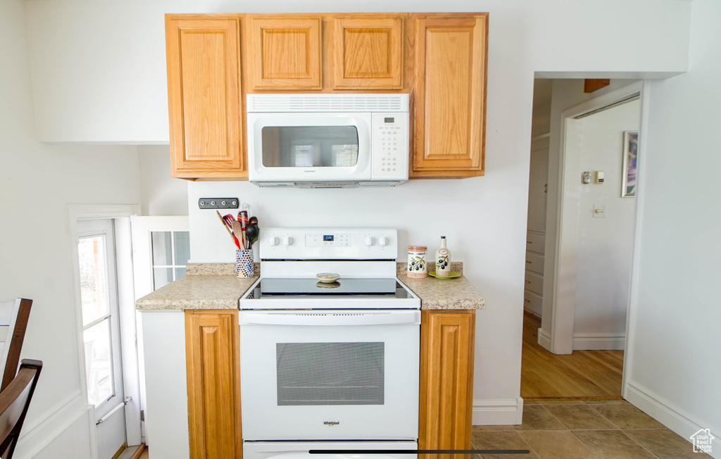 Kitchen with white appliances, light countertops, baseboards, and light tile patterned floors