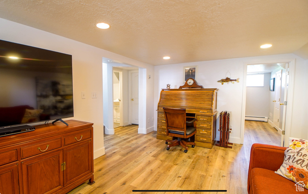 Office with baseboard heating, light wood-style floors, recessed lighting, baseboards, and a textured ceiling