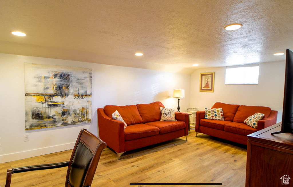 Living area with light wood-type flooring, recessed lighting, baseboards, and a textured ceiling