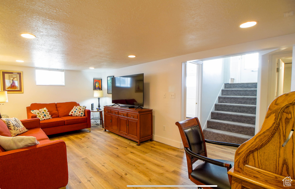 Living area with light wood finished floors, stairs, a textured ceiling, recessed lighting, and baseboards