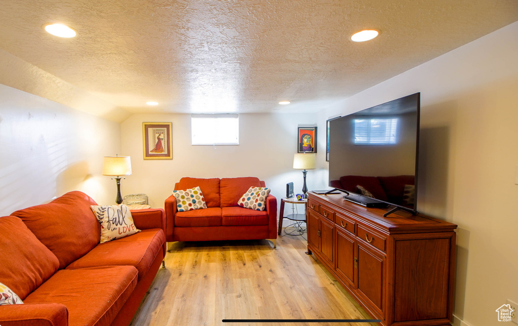Living room featuring a textured ceiling, light wood-style flooring, and recessed lighting