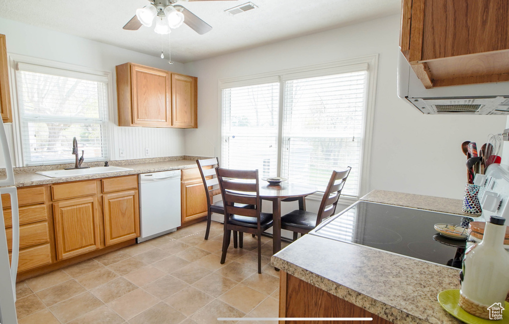 Kitchen featuring white dishwasher, a sink, a ceiling fan, light countertops, and exhaust hood