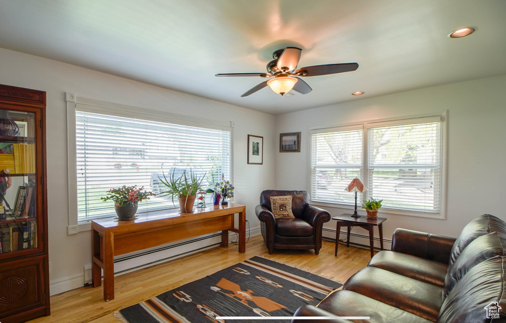 Living room with a baseboard heating unit, plenty of natural light, ceiling fan, recessed lighting, and light wood-style flooring