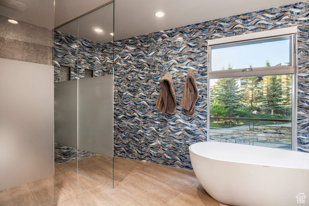 Bathroom with wallpapered walls, a walk in shower, a freestanding tub, tile patterned floors, and recessed lighting