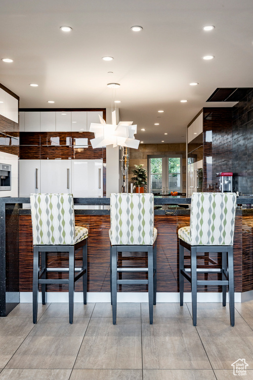 Kitchen with modern cabinets, white cabinets, decorative light fixtures, recessed lighting, and dark countertops