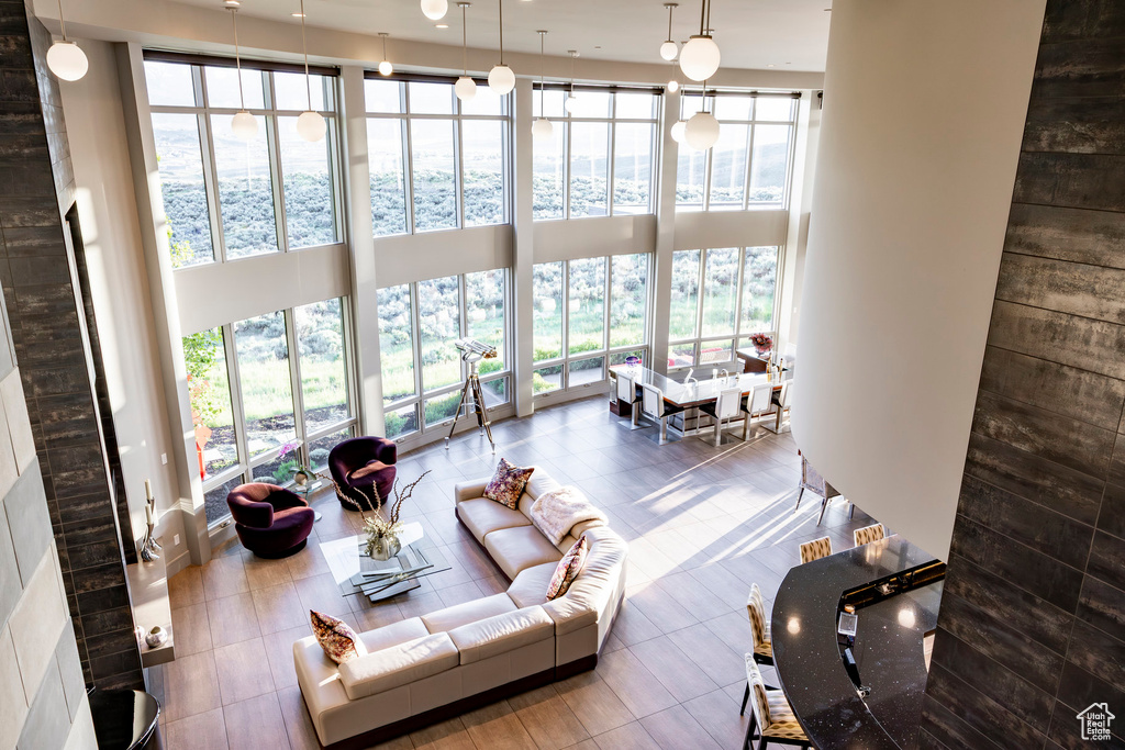 Living area featuring plenty of natural light, a towering ceiling, and tile patterned flooring