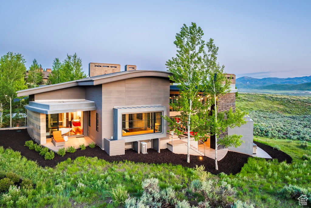 Rear view of house featuring a chimney, a patio area, and a mountain view