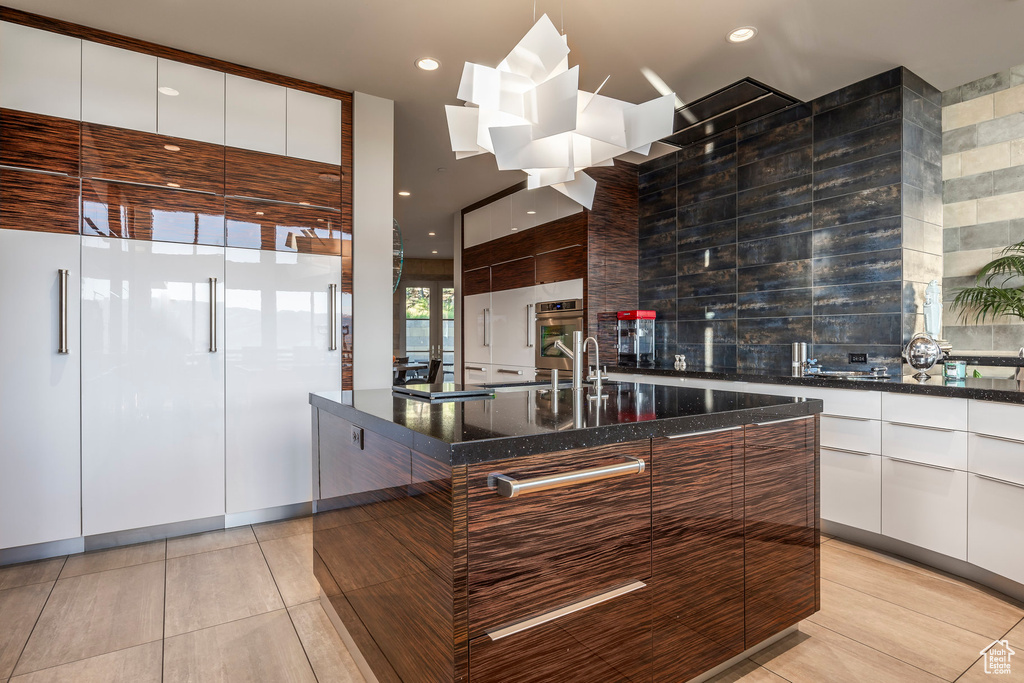 Kitchen with modern cabinets, oven, light tile patterned flooring, dark stone counters, and recessed lighting