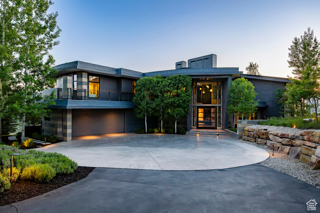 Modern home with curved driveway, an attached garage, and a balcony