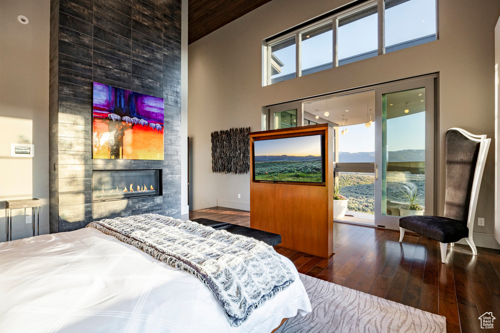 Bedroom with a high ceiling, hardwood / wood-style floors, and a fireplace