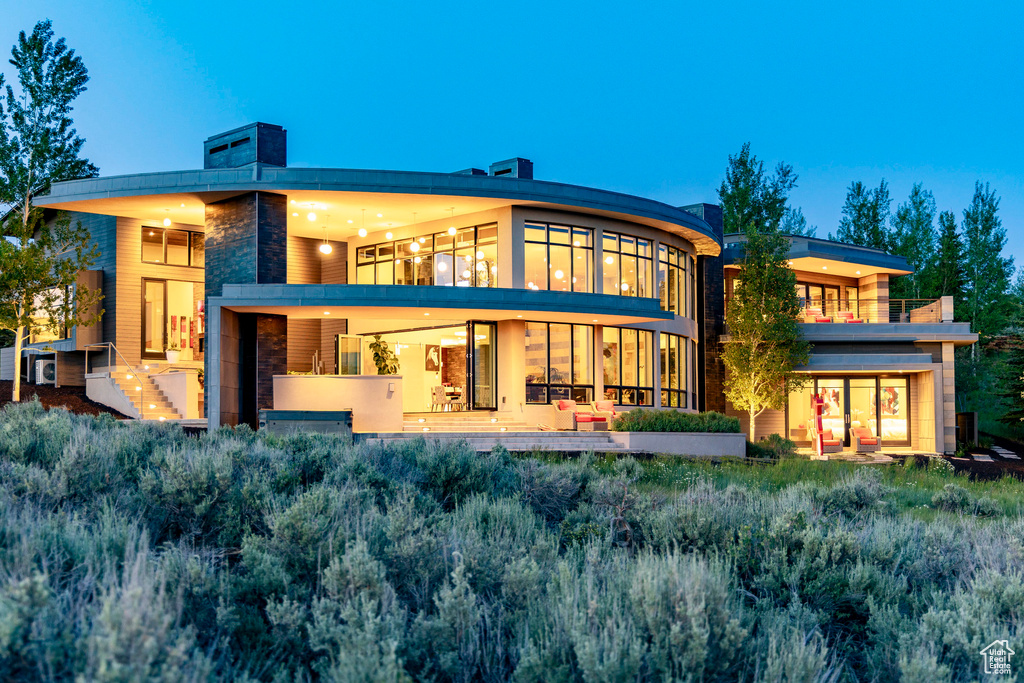 Rear view of house featuring a balcony and stone siding