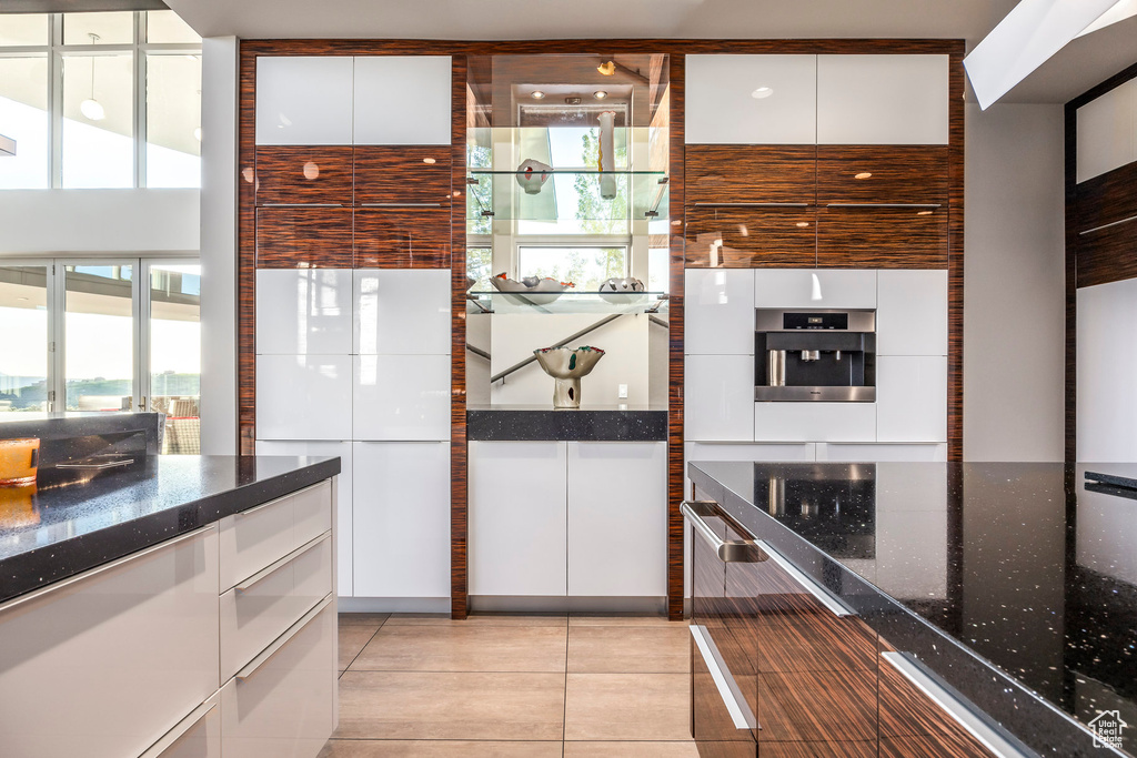Kitchen with modern cabinets, white cabinetry, and dark stone countertops