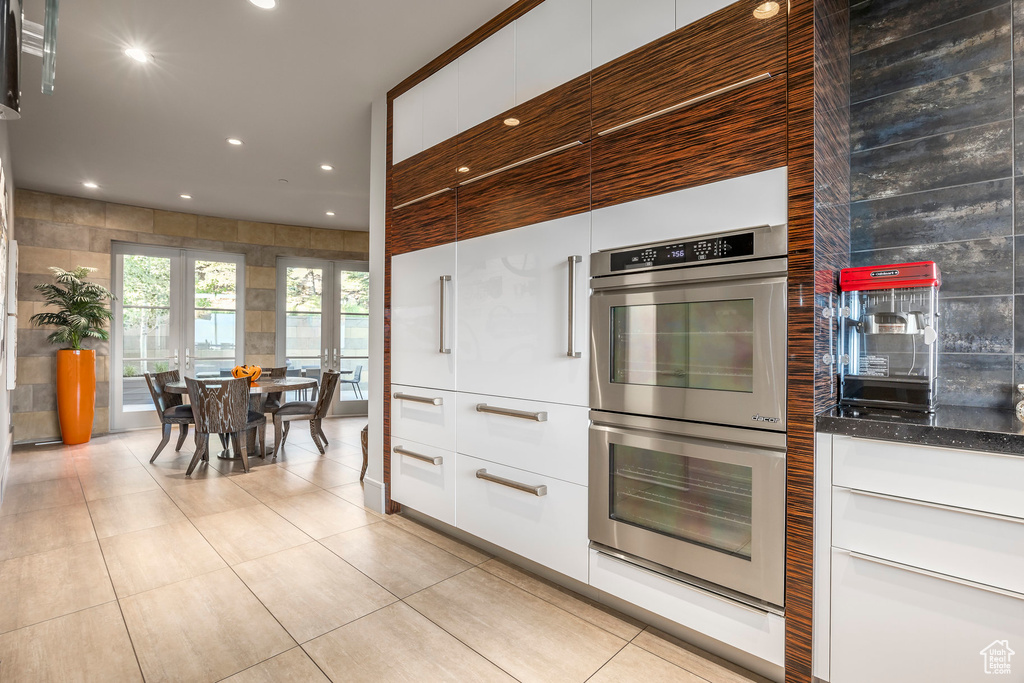 Kitchen featuring stainless steel double oven, modern cabinets, recessed lighting, light tile patterned floors, and white cabinets