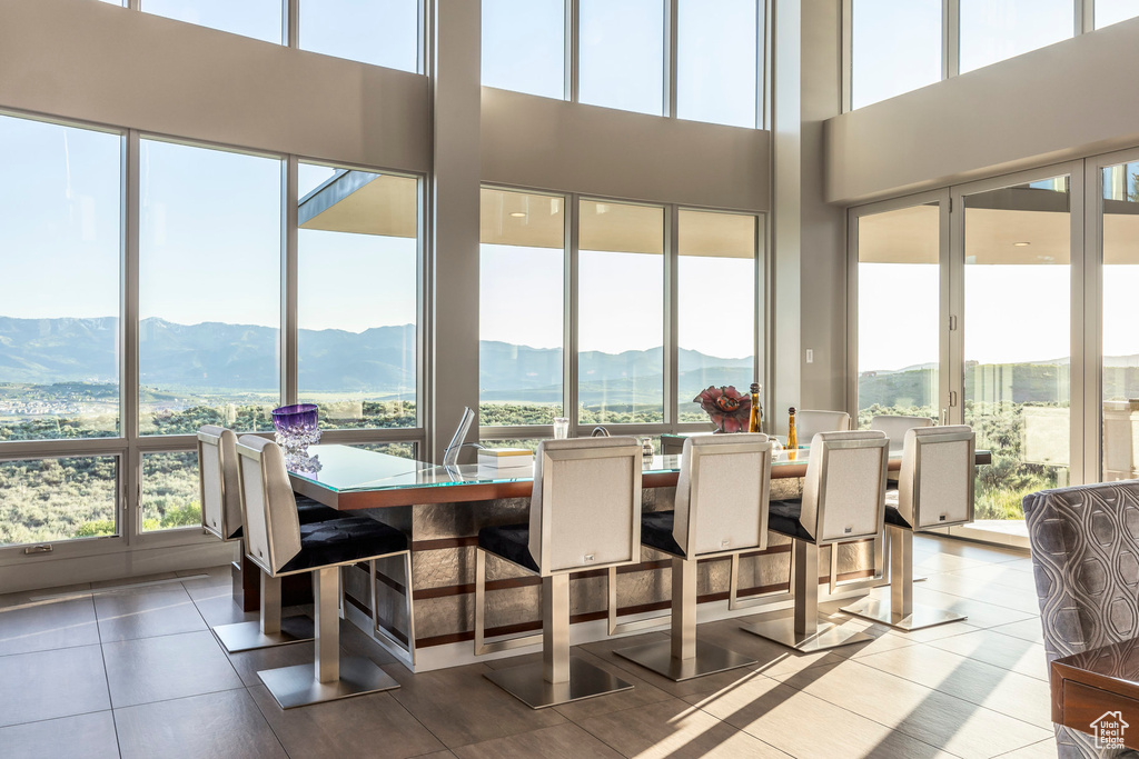 Dining room featuring a mountain view, tile patterned flooring, healthy amount of natural light, and a towering ceiling