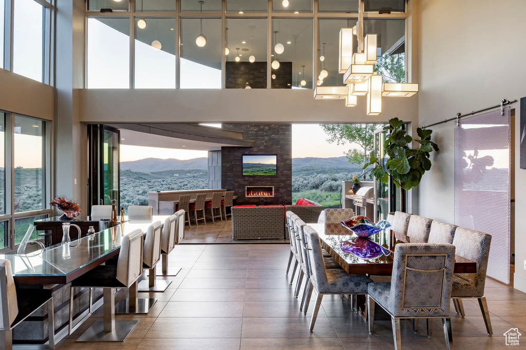 Dining area with healthy amount of natural light, a mountain view, a high ceiling, and a warm lit fireplace