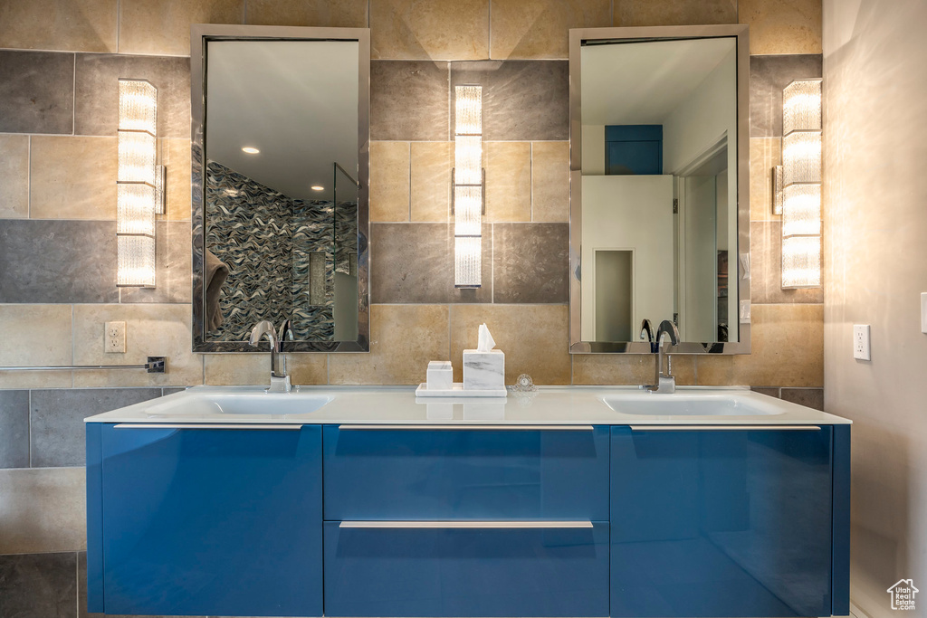 Bathroom featuring double vanity, tile walls, and backsplash