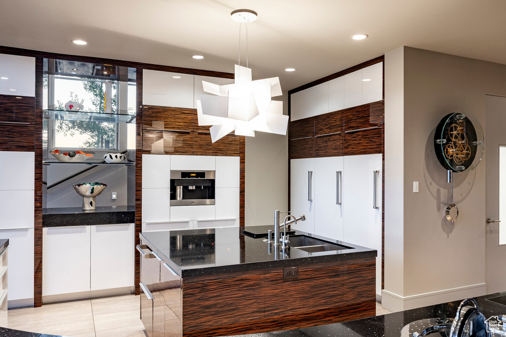 Kitchen with modern cabinets, a sink, oven, white cabinetry, and dark stone counters