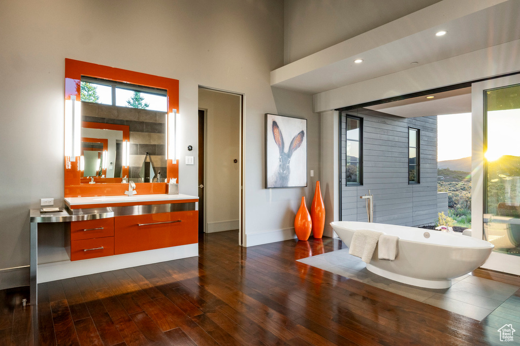 Bathroom with vanity, a freestanding bath, wood-type flooring, baseboards, and a high ceiling