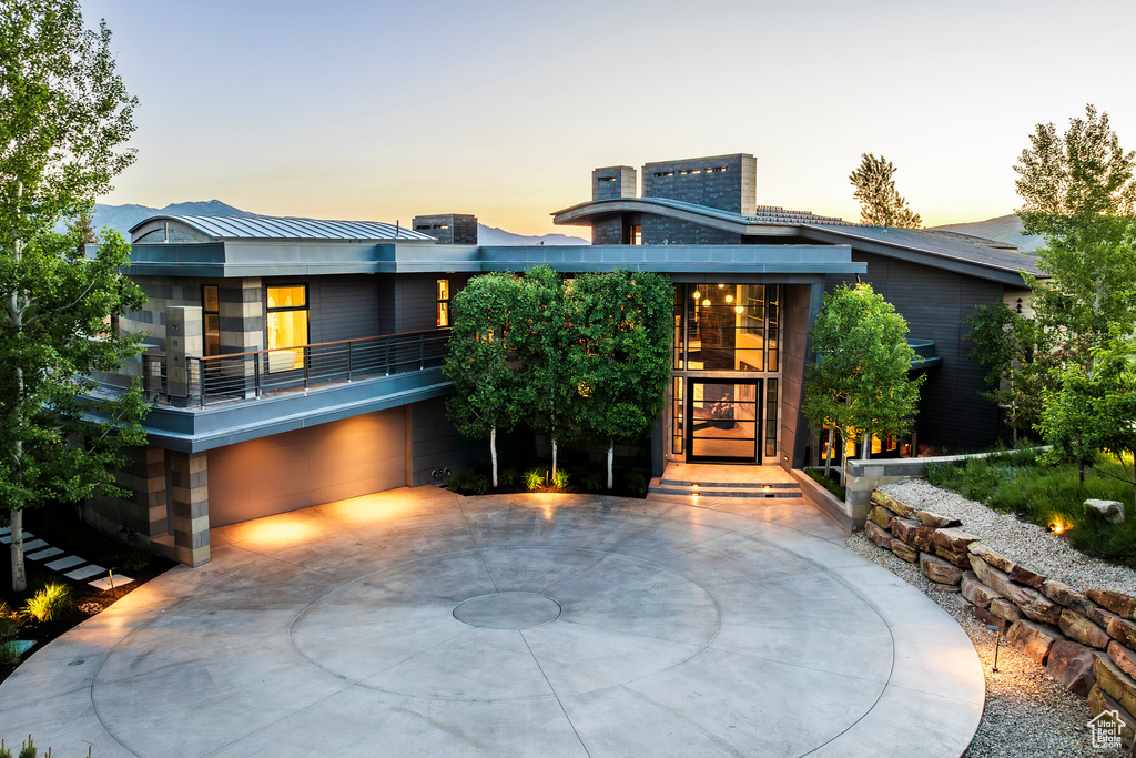 Modern home with an attached garage, curved driveway, and metal roof