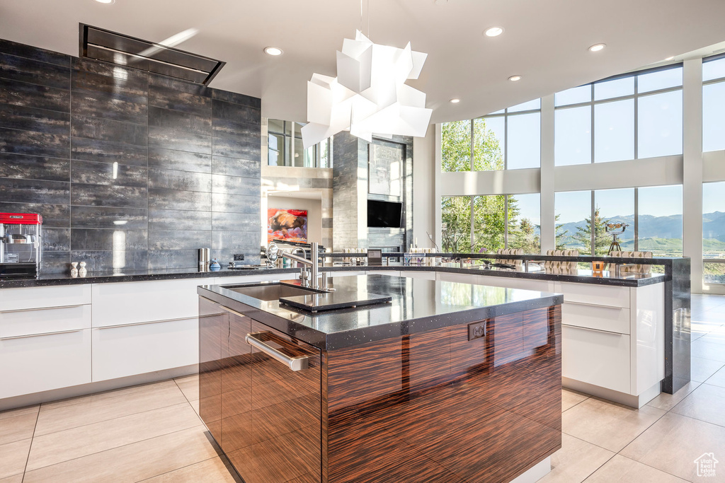 Kitchen featuring modern cabinets, a sink, plenty of natural light, light tile patterned flooring, and a high ceiling