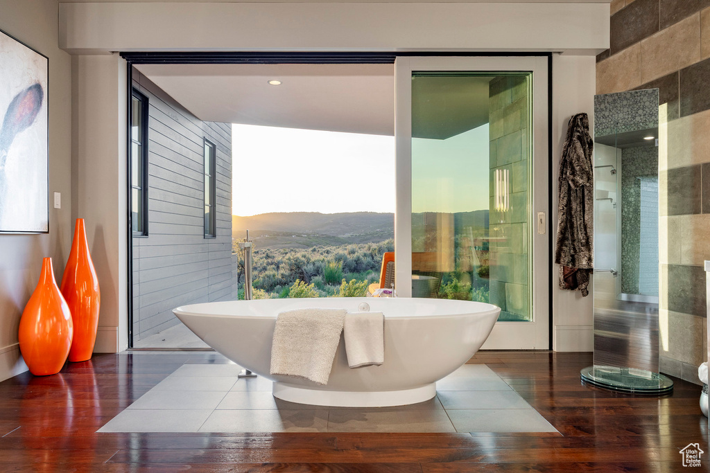 Full bath with a mountain view, hardwood / wood-style flooring, and a soaking tub