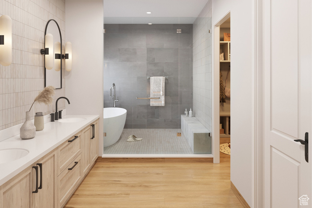 Bathroom featuring a freestanding tub, double vanity, wood finished floors, and recessed lighting