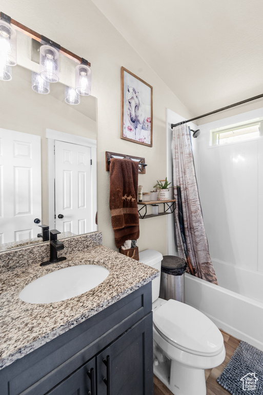 Bathroom featuring vanity, toilet, shower / tub combo with curtain, wood finished floors, and vaulted ceiling