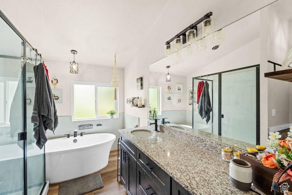 Bathroom with vanity, wood finished floors, a stall shower, a soaking tub, and vaulted ceiling