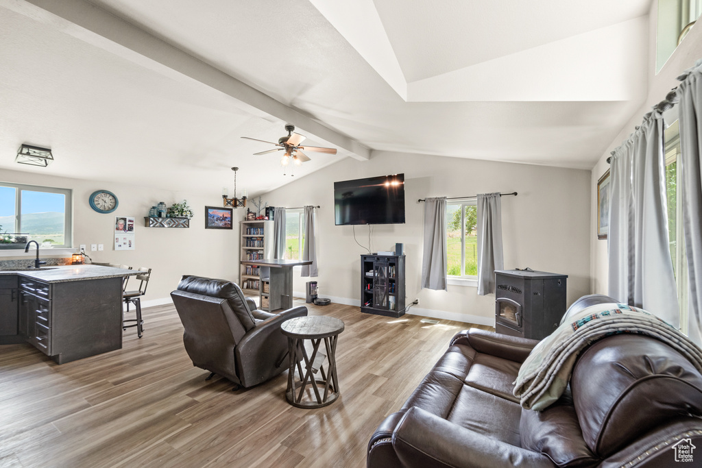 Living area featuring a wood stove, light wood finished floors, ceiling fan, and baseboards
