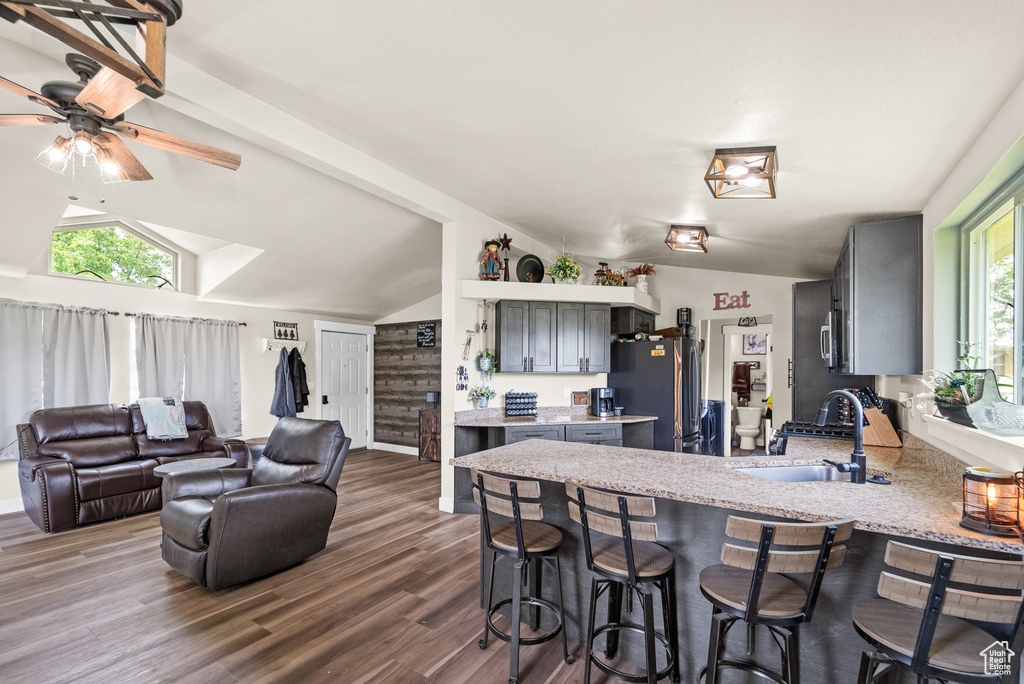 Kitchen with stainless steel appliances, a sink, a peninsula, lofted ceiling, and a kitchen breakfast bar