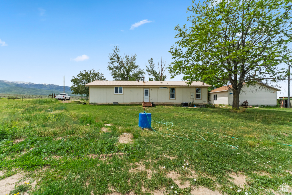 Rear view of house with a lawn, a mountain view, and central AC