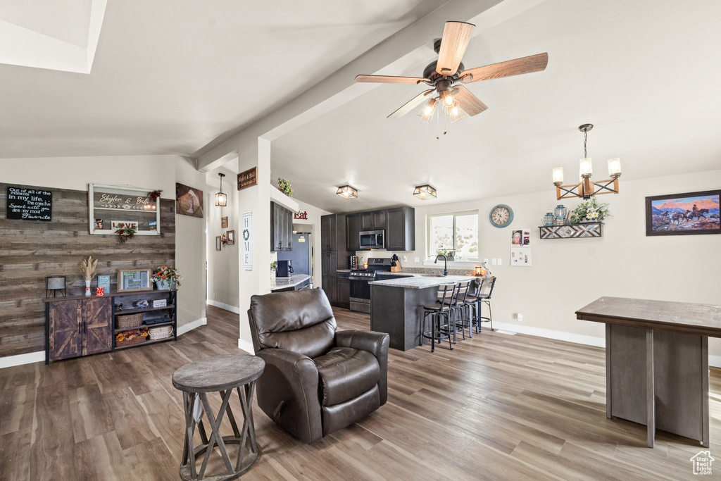 Living room with vaulted ceiling, wood finished floors, baseboards, and a ceiling fan