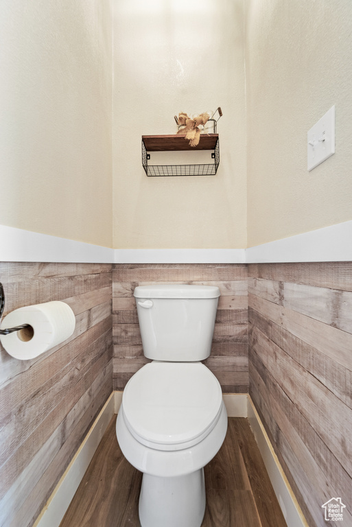 Bathroom featuring toilet, a wainscoted wall, and wood finished floors