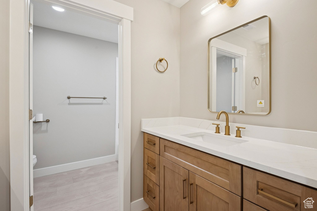 Bathroom featuring toilet, vanity, baseboards, and wood finished floors