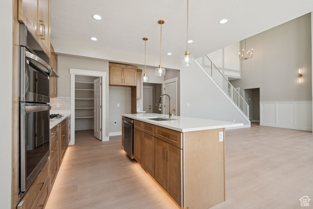 Kitchen with a sink, light wood-type flooring, dishwasher, recessed lighting, and decorative backsplash
