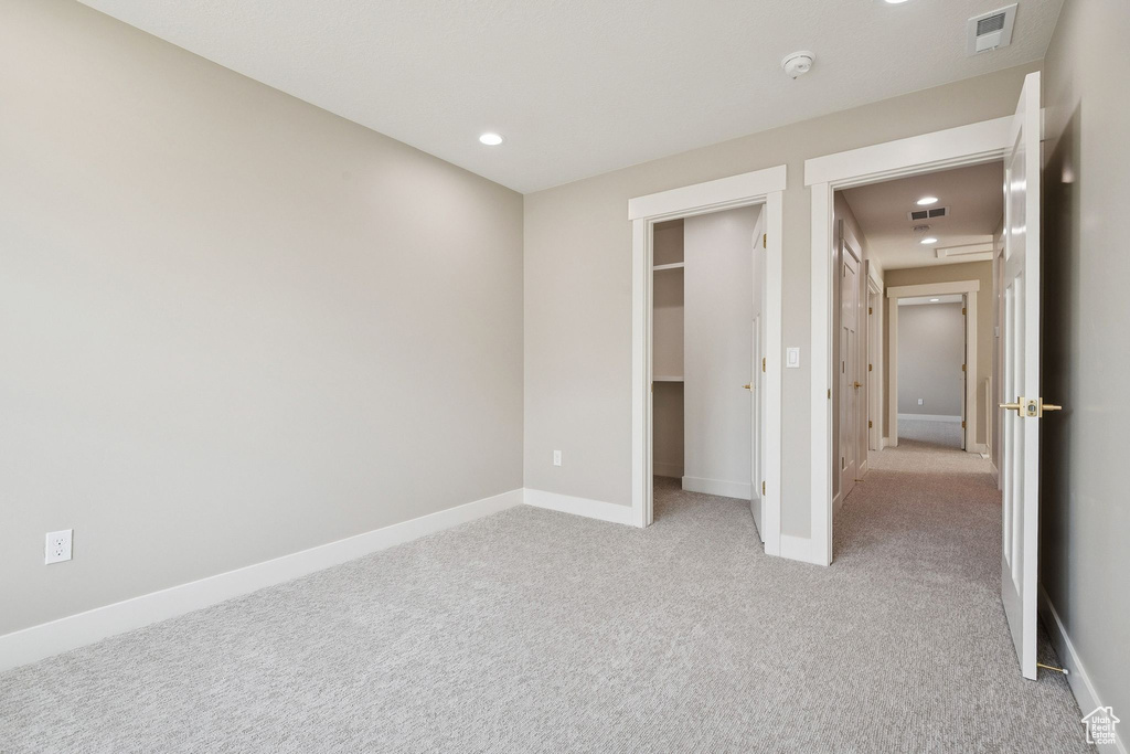 Unfurnished bedroom with light carpet, recessed lighting, baseboards, and a spacious closet