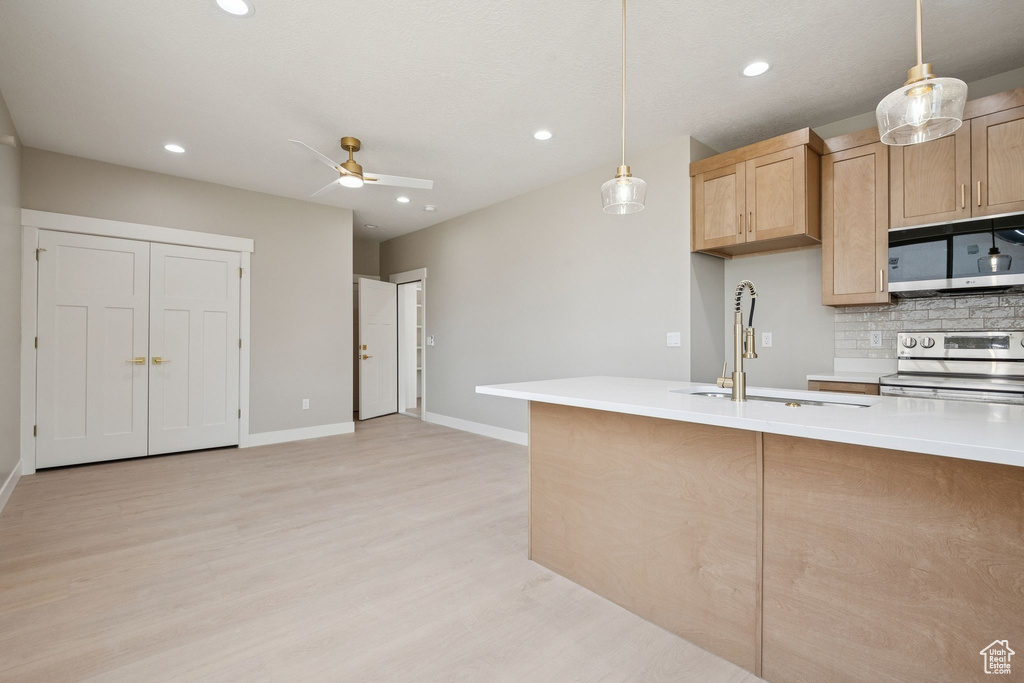Kitchen with black microwave, stainless steel range with electric stovetop, a sink, light wood-style floors, and a ceiling fan