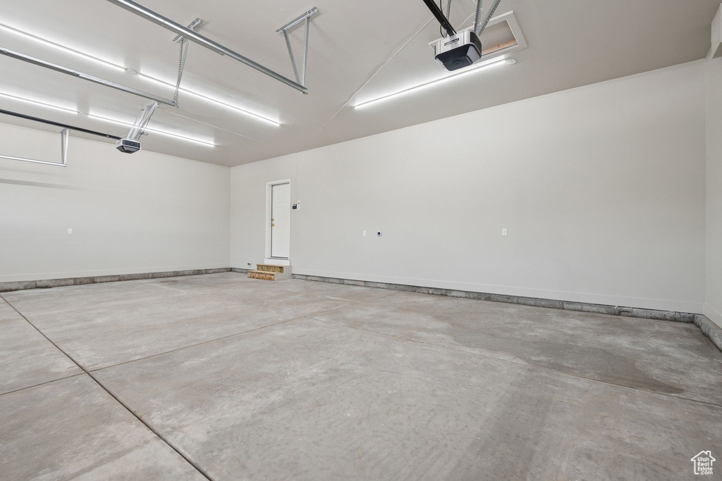 Garage featuring a garage door opener and baseboards