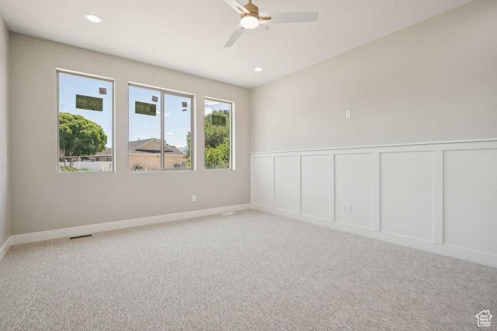 Carpeted empty room featuring a ceiling fan, a wainscoted wall, recessed lighting, and a decorative wall