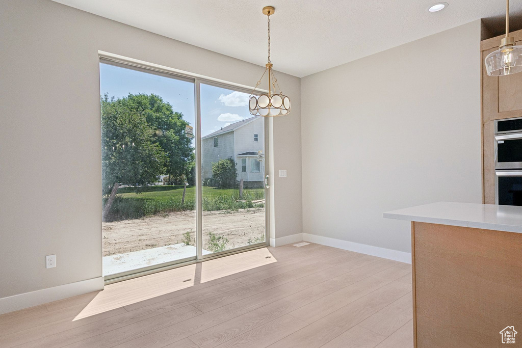 Unfurnished dining area with light wood-style floors, baseboards, a chandelier, and recessed lighting