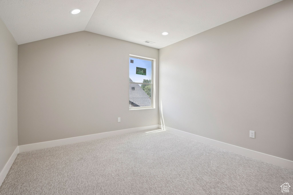 Spare room featuring carpet flooring, recessed lighting, baseboards, and vaulted ceiling