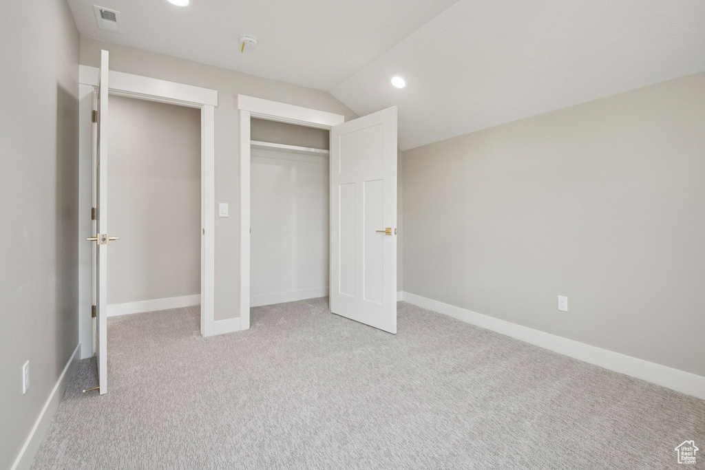 Unfurnished bedroom with light carpet, vaulted ceiling, recessed lighting, a closet, and baseboards