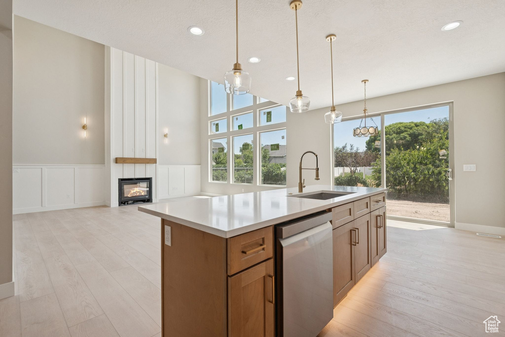 Kitchen featuring stainless steel dishwasher, a sink, light wood-type flooring, plenty of natural light, and recessed lighting