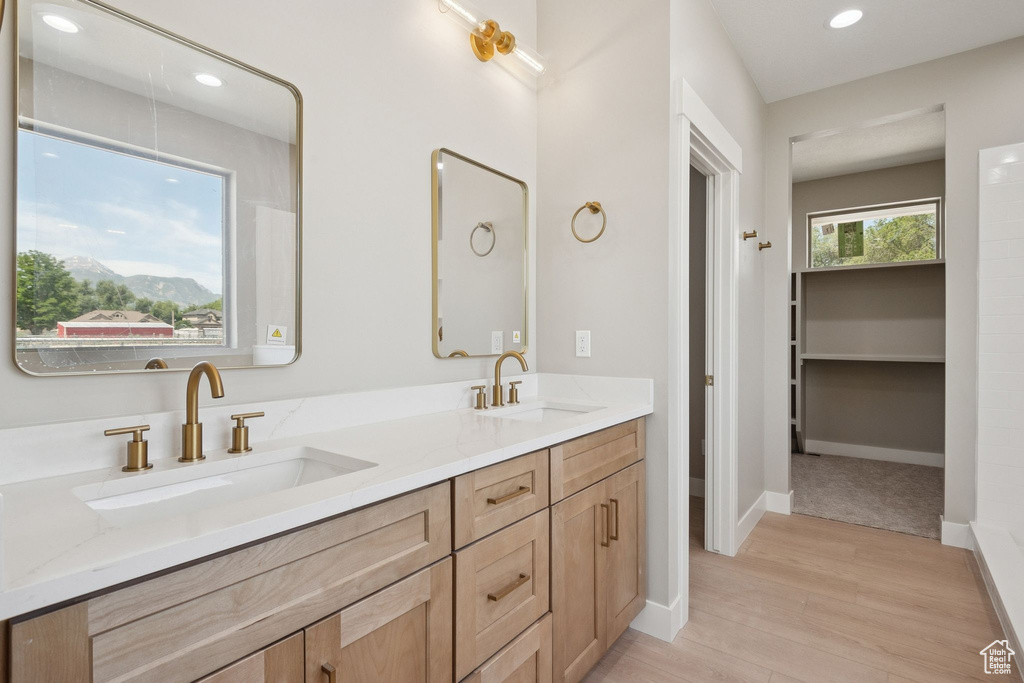 Bathroom featuring double vanity, wood finished floors, recessed lighting, baseboards, and a mountain view
