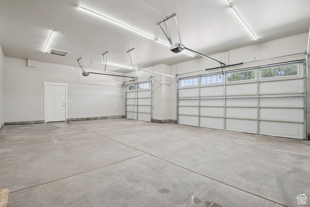 Garage featuring a garage door opener and baseboards