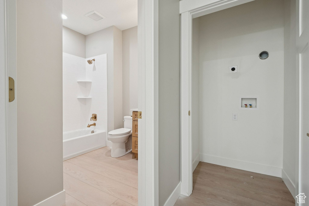 Full bathroom featuring toilet, wood finished floors, shower / tub combination, and baseboards